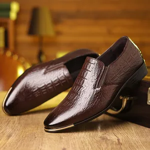 Detalle macro de mocasines de cuero con relieve de cocodrilo marrón y adornos dorados