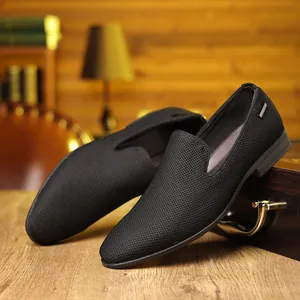Détail de mocassins en maille noire avec garniture argentée sur un bureau en bois