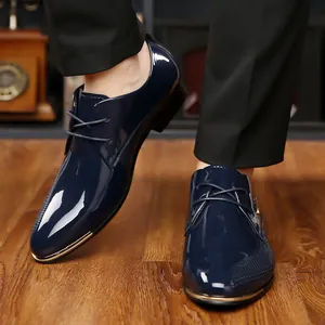 Macro shot of blue patent leather derby shoe with gold metal toe cap and punched texture