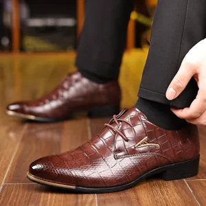 Detail of dark brown crocodile-patterned dress shoes with gold metal toe cap and V-logo