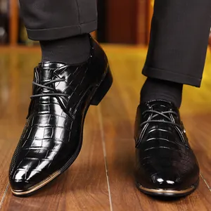 Detail of black oxford shoes with crocodile pattern and golden metal pointed toe trim
