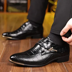 Detail of black dress shoe with crocodile texture, gold buckle, and metal toe cap decoration