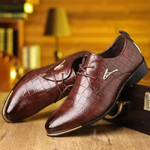 Detail of brown crocodile embossed leather shoe with gold metal toe cap and buckle