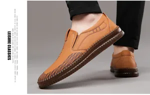 Detail of hand-stitched seams and brown texture on men's tan slip-on leather loafers