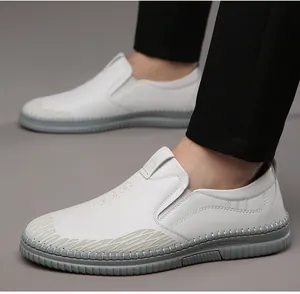 Detail view of white men's slip-on loafers featuring non-slip gray rubber soles and embossed sides