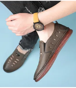 Detail of hand-stitched brown leather sandals with breathable cutouts and red rubber sole