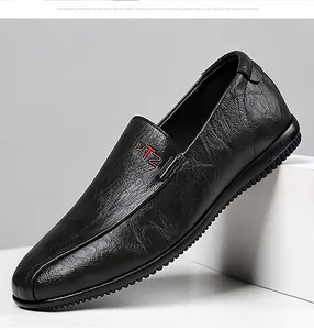 Close-up of black leather loafers showing grainy texture and red embroidery detail