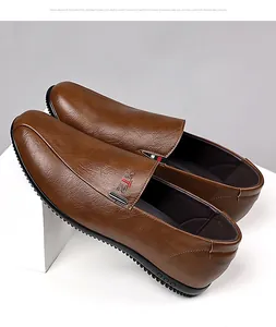 Detailed macro view of brown leather loafers featuring ZIK metal ornament and red-white ribbon