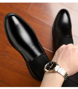 First-person view of shiny black leather slip-on loafers worn on dark wooden flooring