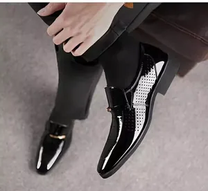 Detail von schwarzen Lacklederschuhen mit goldener Schnalle und Lochmuster-Design