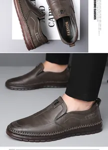 Detail van donkerbruine leren loafers met metalen B-logo en contraststiksels