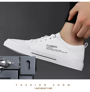 Detail van witte herensneakers met veters en zwarte tekst op de zijkant van de schoen