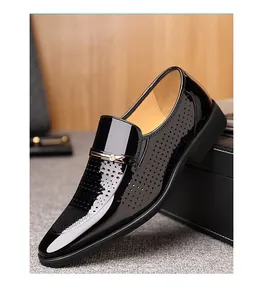 Details von schwarzen Lacklederslippern mit Laser-Löchern und goldener Metallschnalle