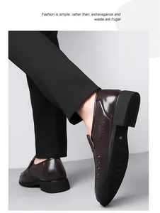 Close-up of brown leather loafers with side cutouts and black rubber sole on model