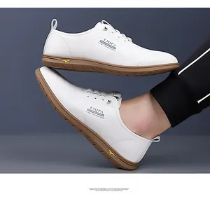 Detail view of white leather men's loafers with brown rubber soles and side logo