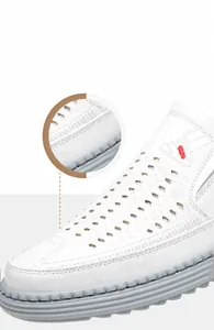 Détail de sandales homme en cuir blanc avec dessus ajouré et broderie rouge sur le côté