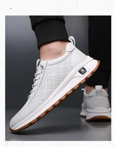 Close-up of white leather men's sneakers featuring perforated side vents and gum rubber sole