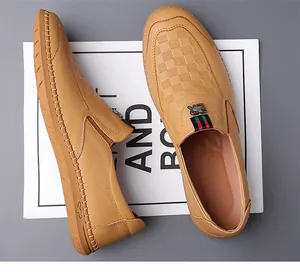 Detalle de mocasines de cuero camello con grabado de cuadros y adorno de cinta a rayas