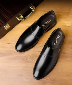 Detailed view of black matte leather shoes with punch line decor on wooden floor