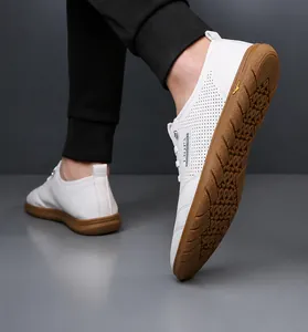 Detailansicht der weißen Leder-Slipper mit perforierten Seiten und brauner Gummisohle