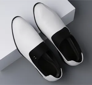 Top view of black and white leather loafers with detailed stitching on white pedestal