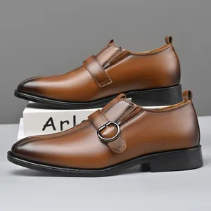 Dettaglio di scarpa da lavoro in pelle marrone con fibbia laterale e punta sfumata scura