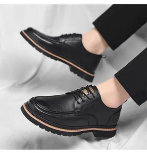 Detail of black leather brogue shoes with thick rubber soles and brown stitching accents