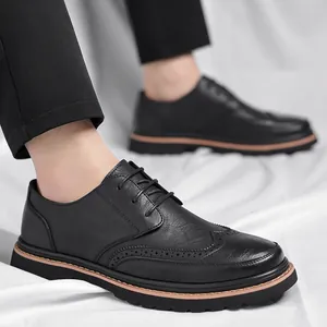 Classic black Brogue shoes for men with wingtip carving and thick soles on white fabric