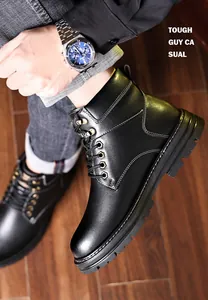 Close-up of men's matte black leather boots with side stitching on wooden floor