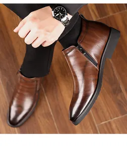 Detail view of brown men's leather boots with side zipper and elegant wingtip brogue detailing
