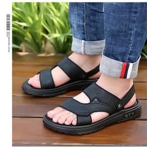 Detail van zwarte lederen sandalen met hielband op een houten buitenvloer in zon