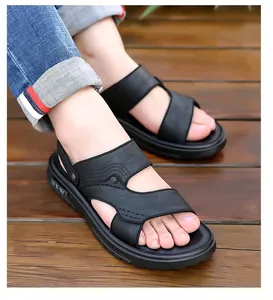 Detail van zwarte leren herensandalen met een dikke rubberen zool en NEW-belettering