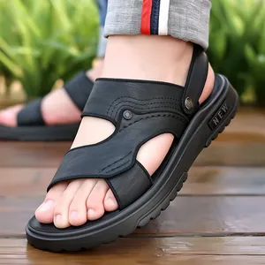 Heren sandalen van zwart leer met dikke rubberen zool en stiksels op een houten terras