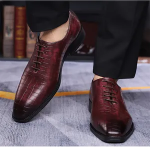 Dettaglio delle scarpe da lavoro in pelle bordeaux da uomo con goffratura coccodrillo