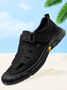Dettaglio di sandali in pelle nera traspiranti con velcro su sfondo di spiaggia estiva