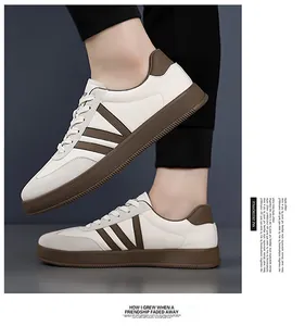 Detail van witte leren sneaker met bruine V-streep en platte rubberen zool voor heren