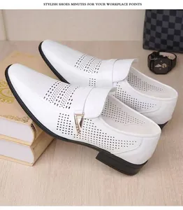 Vue de dessus de chaussures en cuir perforé blanc avec boucle métal sur fond bois clair