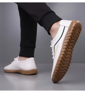 Detail view of white leather shoe showing anti-slip brown rubber sole and side stripes