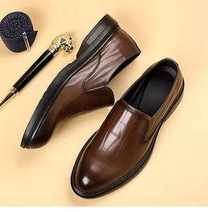 Detail van bruine loafers met krokodillenprint, een donkerblauwe das en gouden pen