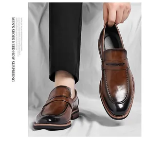 Close-up of brown leather penny loafers with black gradient toe and premium glossy finish