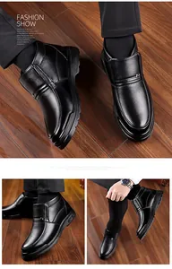 Detail of men's black leather ankle boots with metal H-buckle on dark wood floor