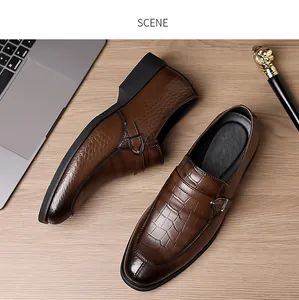 Detail of dark brown monk strap shoe with crocodile embossed texture on a wooden table