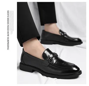 Gros plan de mocassins en cuir noir avec boucle en métal portés avec costume sombre