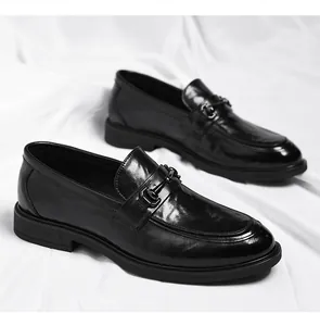 Détail de mocassins en cuir verni noir avec boucle en métal et semelle épaisse en gomme