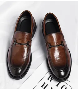 Gros plan de mocassins marron foncé en cuir poli avec détail de boucle métallique