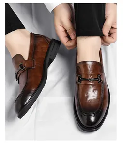 Détail de mocassins en cuir dégradé marron avec boucle mors métallique aux pieds