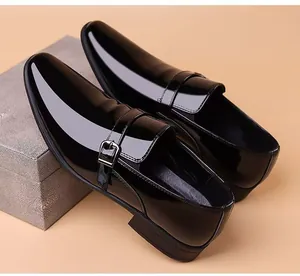 Detalle de zapato monk strap en charol negro con hebilla metálica plateada