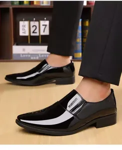 Detail of black glossy leather loafers with silver fashion text and formal trousers