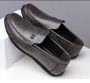 Close-up of handmade stitching and metal logo on dark grey men's leather loafer