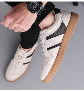 Detail shot of men leather sneaker featuring black stripes and brown rubber sole on feet
